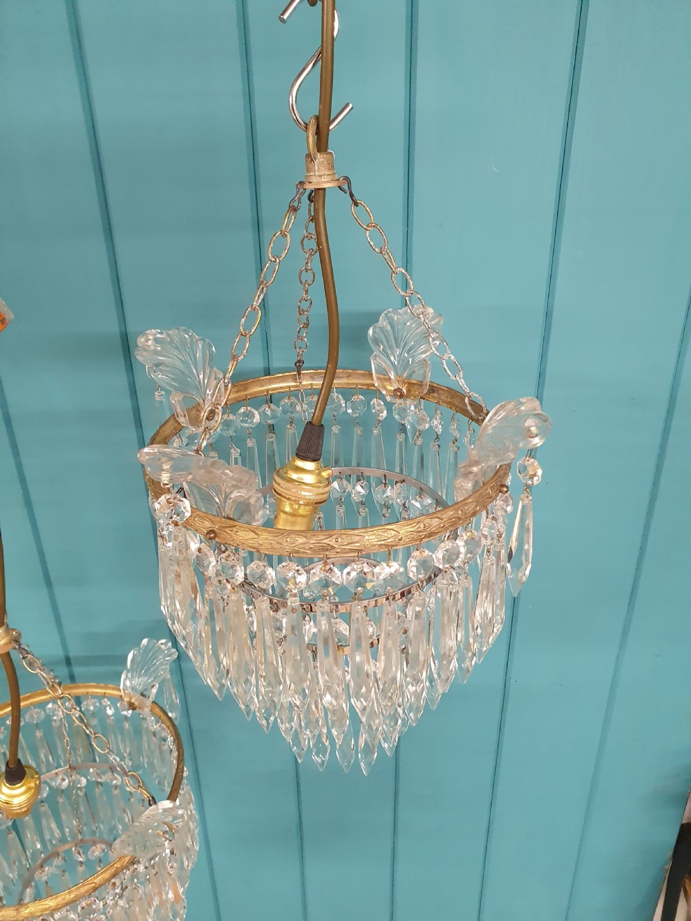 A pair of matching eleven-inch ceiling chandeliers featuring brass frames suspended with tiers of clear cut crystal glass spikes and drops. View III