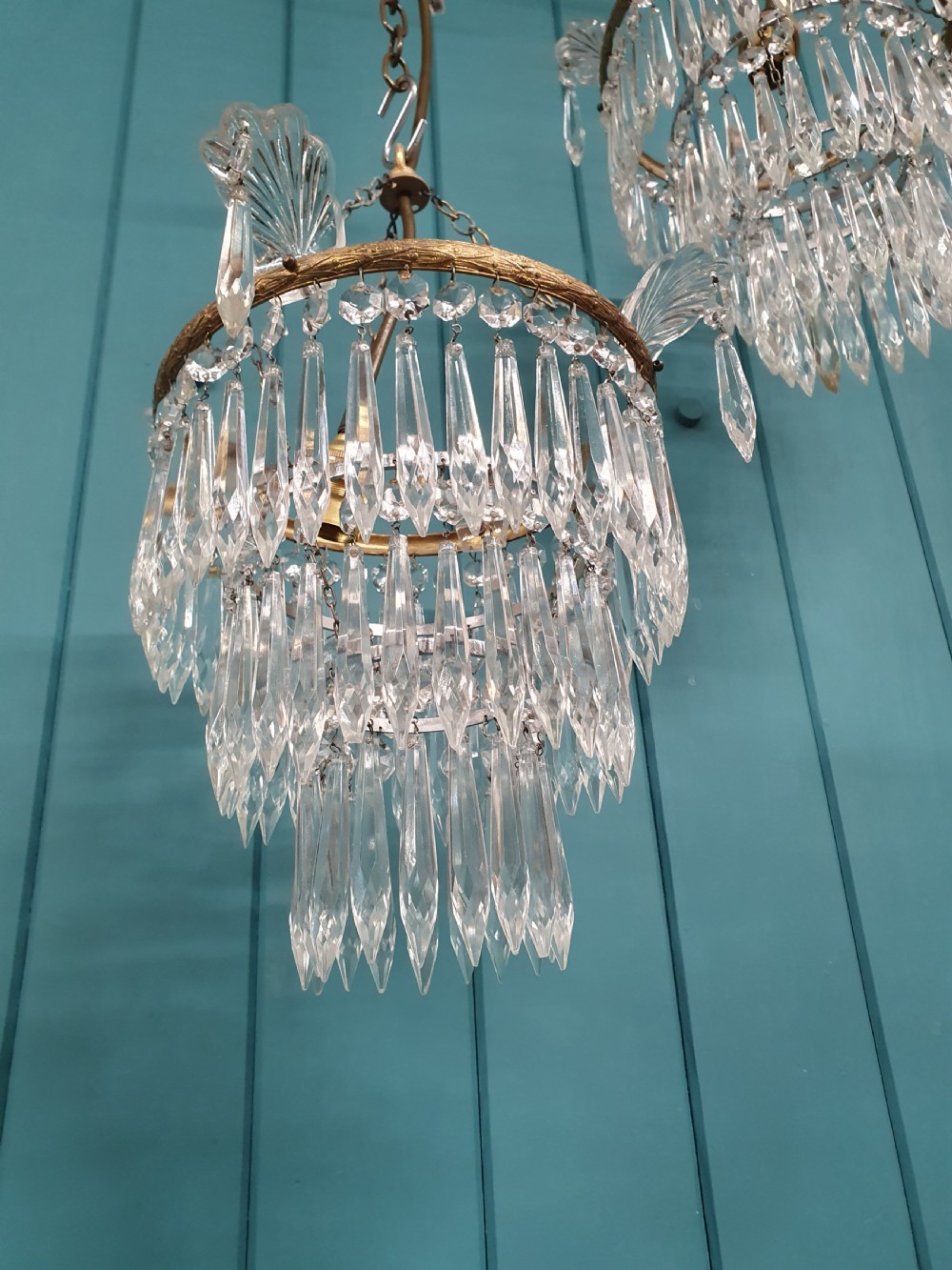A pair of matching eleven-inch ceiling chandeliers featuring brass frames suspended with tiers of clear cut crystal glass spikes and drops. View IV