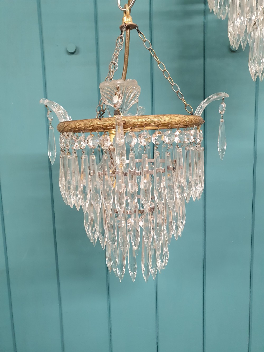 A pair of matching eleven-inch ceiling chandeliers featuring brass frames suspended with tiers of clear cut crystal glass spikes and drops. View VI