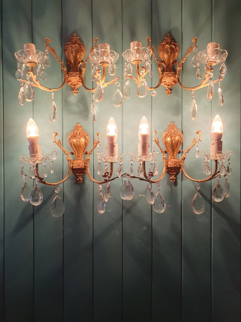 A set of four early 20th-century French Rococo revival gilt brass twin-arm wall sconces decorated with cut crystal glass droplets. View IV