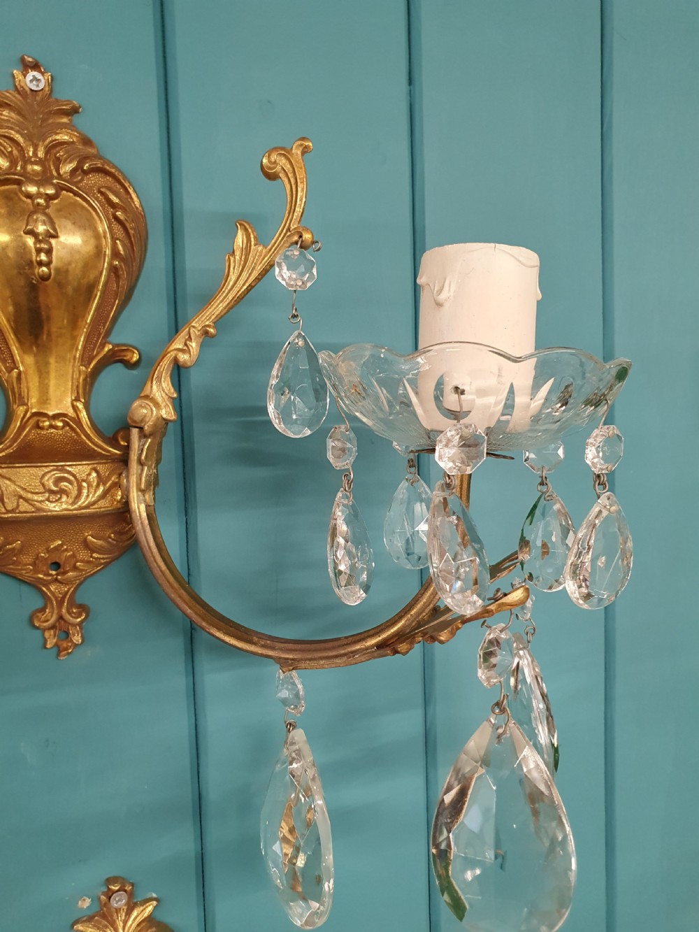 A set of four early 20th-century French Rococo revival gilt brass twin-arm wall sconces decorated with cut crystal glass droplets. View V