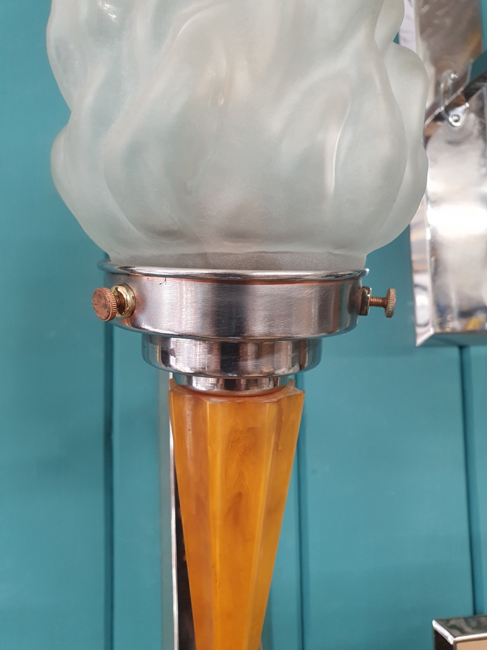 A set of four Art Deco torch-style wall lights featuring molded frosted glass flame shades set atop amber-coloured tapered stems and polished metal wall mountings. View II