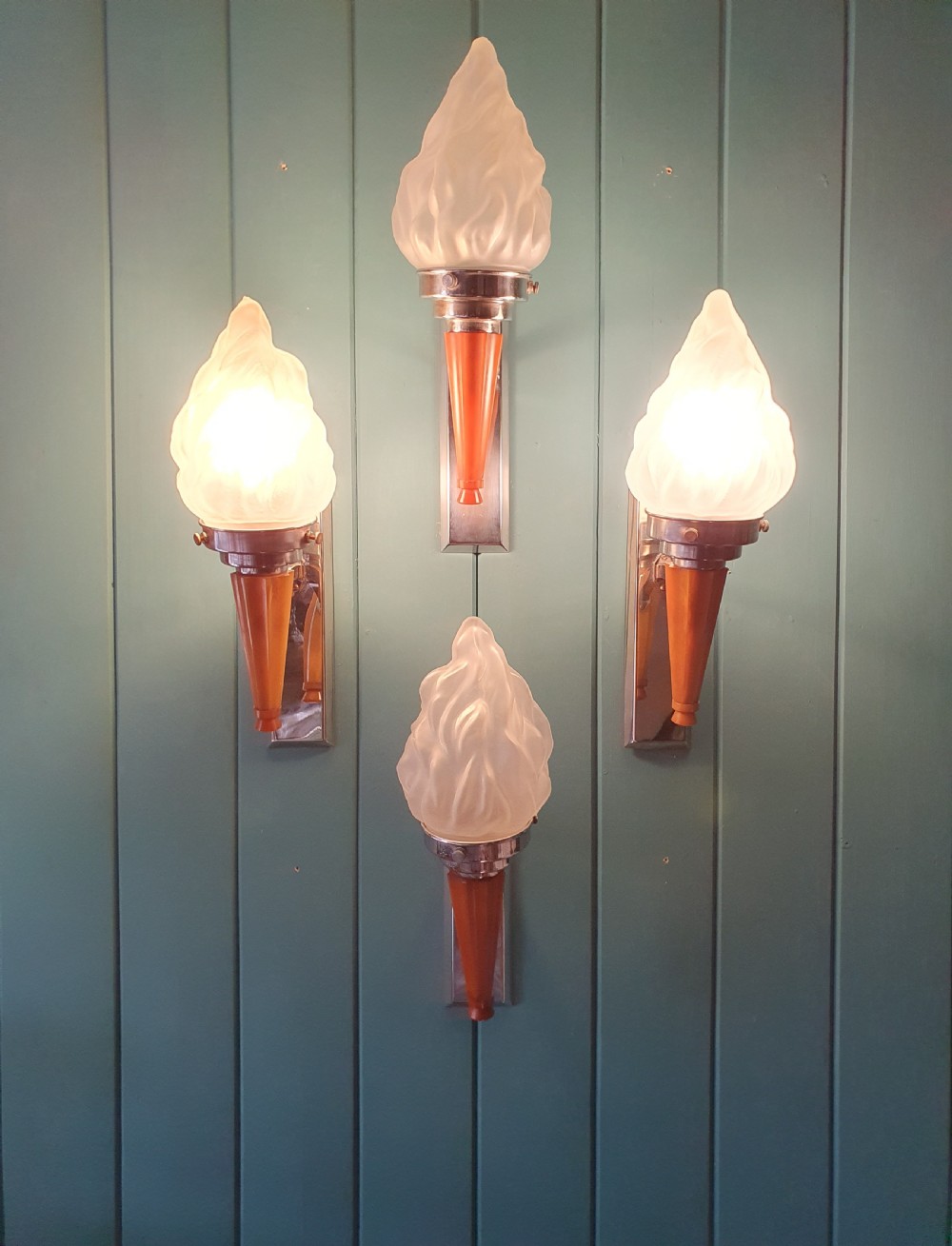 A set of four Art Deco torch-style wall lights featuring molded frosted glass flame shades set atop amber-coloured tapered stems and polished metal wall mountings. View III