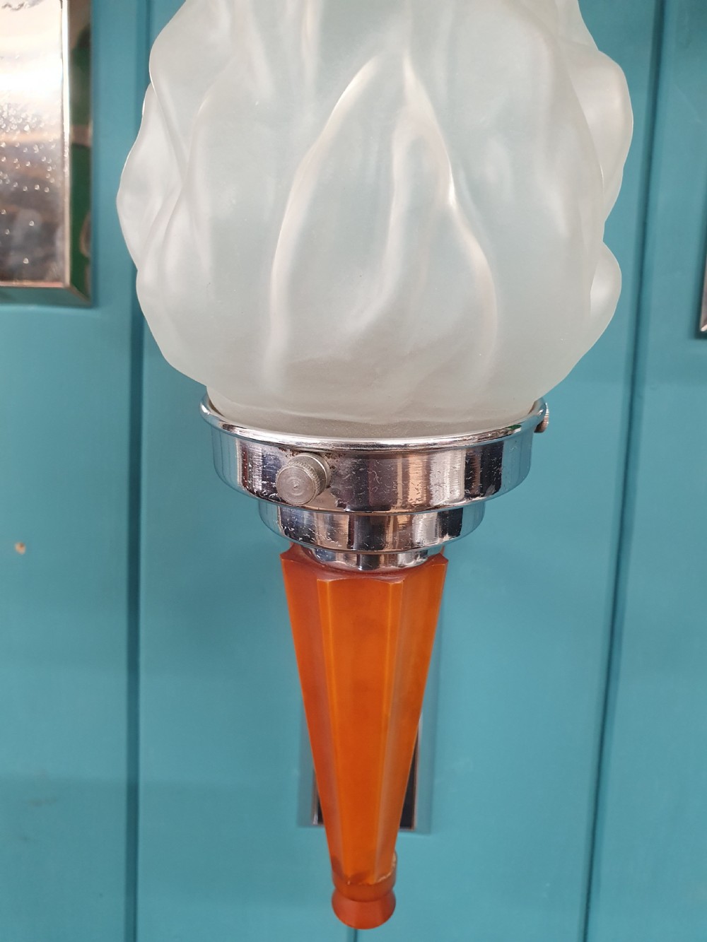 A set of four Art Deco torch-style wall lights featuring molded frosted glass flame shades set atop amber-coloured tapered stems and polished metal wall mountings. View VII