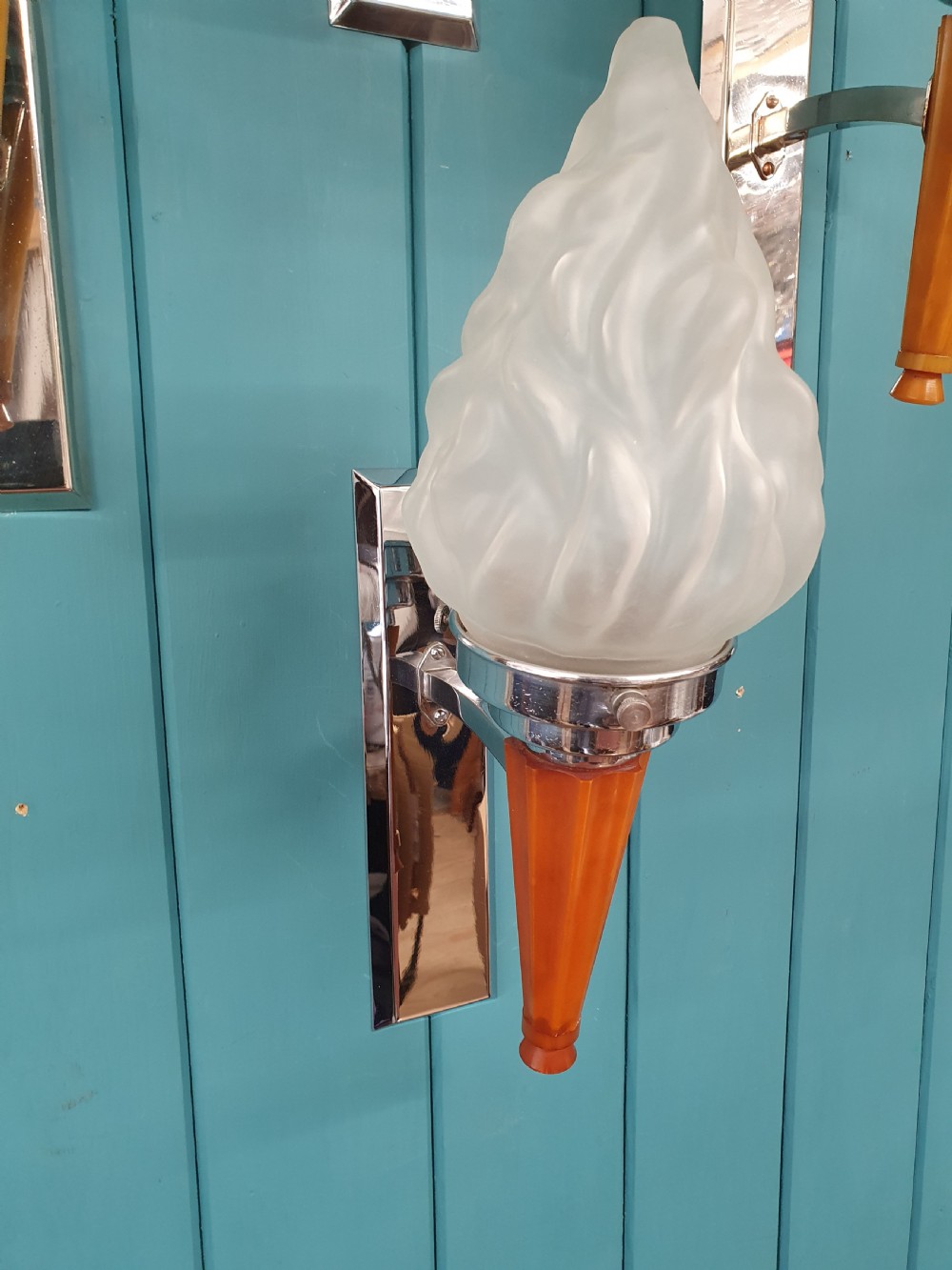 A set of four Art Deco torch-style wall lights featuring molded frosted glass flame shades set atop amber-coloured tapered stems and polished metal wall mountings. View VIII
