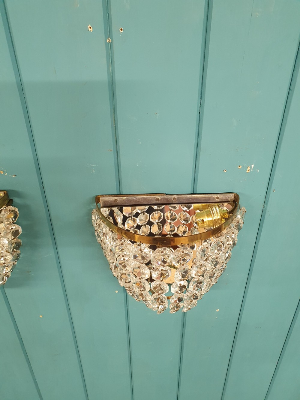 A pair of antique crystal bag wall lights featuring semi-circular pouch frames filled with faceted glass crystal beads below brass bands. View V