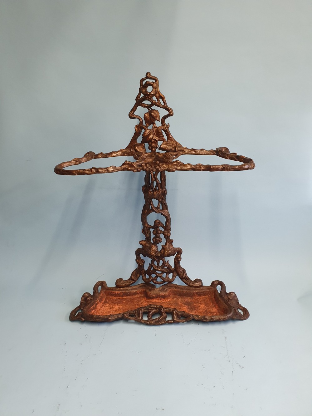 A Victorian cast iron stick stand featuring naturalistic branch and foliage decoration with a drip tray base.