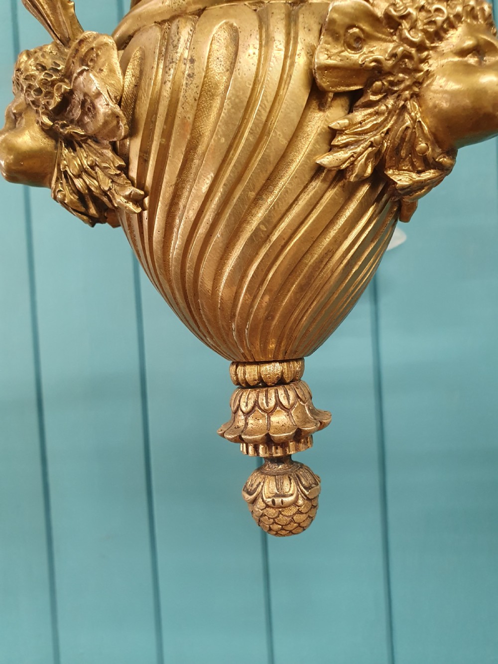 A cast brass three-arm chandelier featuring cherub head reliefs on a central fluted body and floral frosted glass shades. View V