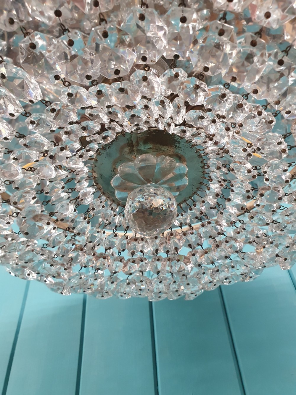 A circular ceiling chandelier featuring suspended octagonal cut glass crystal beads in a basket shape with decorative glass rosettes along the upper rim. View VI