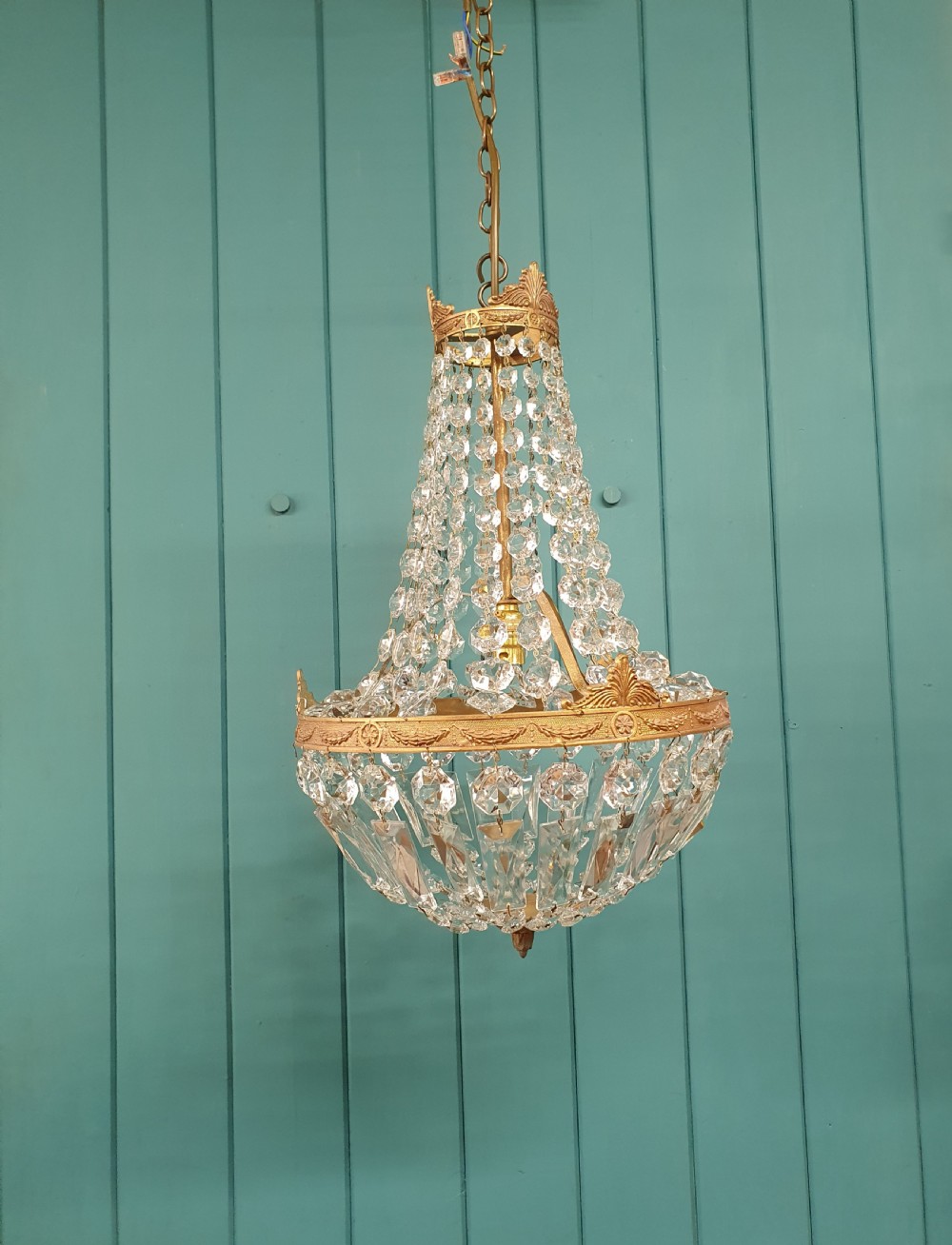 A cut glass crystal tent and bag chandelier featuring concentric tiers of glass beads suspended from a chased brass rim.