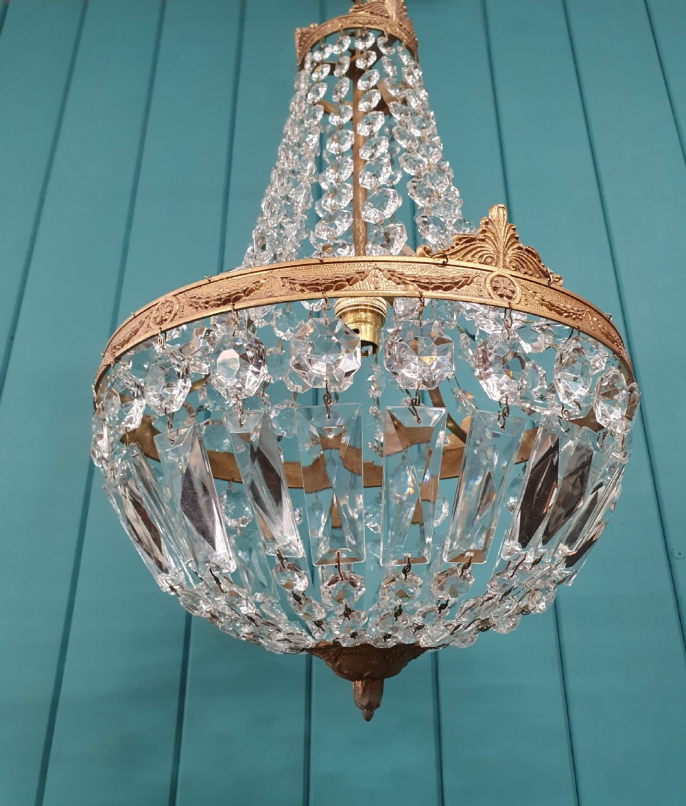 A cut glass crystal tent and bag chandelier featuring concentric tiers of glass beads suspended from a chased brass rim. View VI