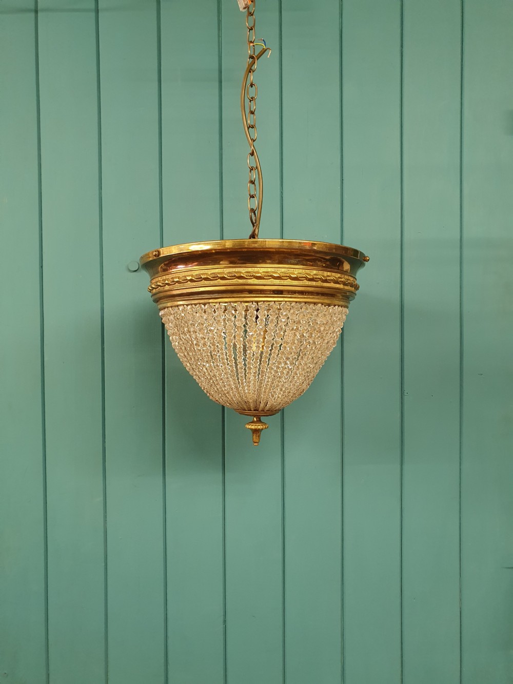 An early 20th-century ceiling light featuring a circular brass band with twisted detail above cascading strands of clear cut glass beads terminating at a brass finial. View VIII