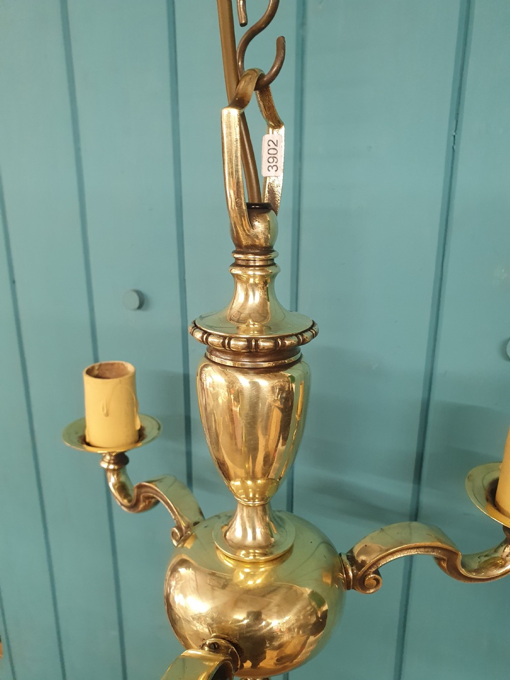 An early 20th-century three-arm brass chandelier featuring a central baluster stem, curved branches, faux candle sleeves, and a hanging chain. View V
