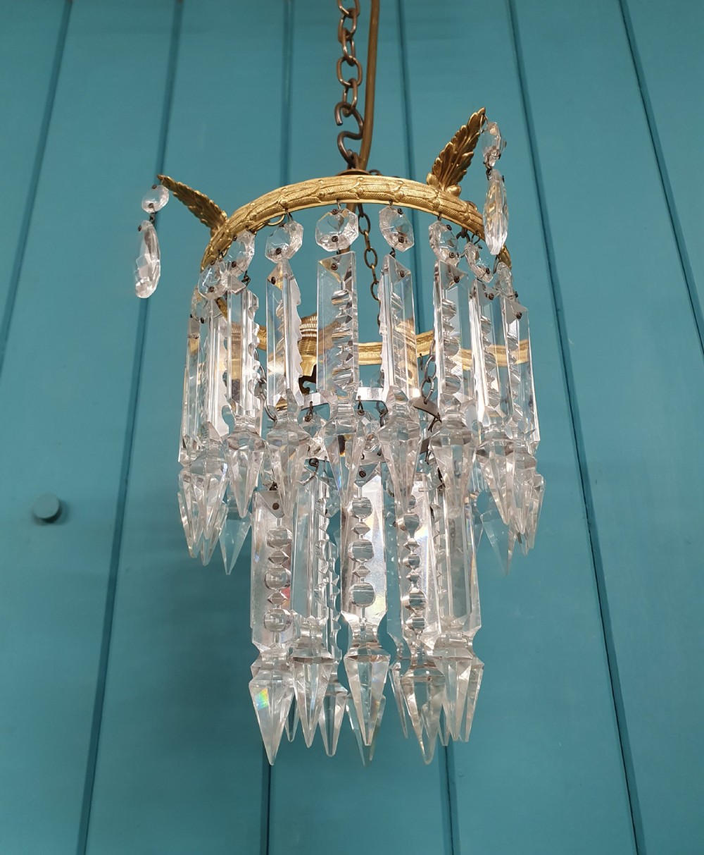An early 20th-century ceiling chandelier featuring a circular brass ring adorned with tiered hanging clear crystal prisms suspended from a chain. View III