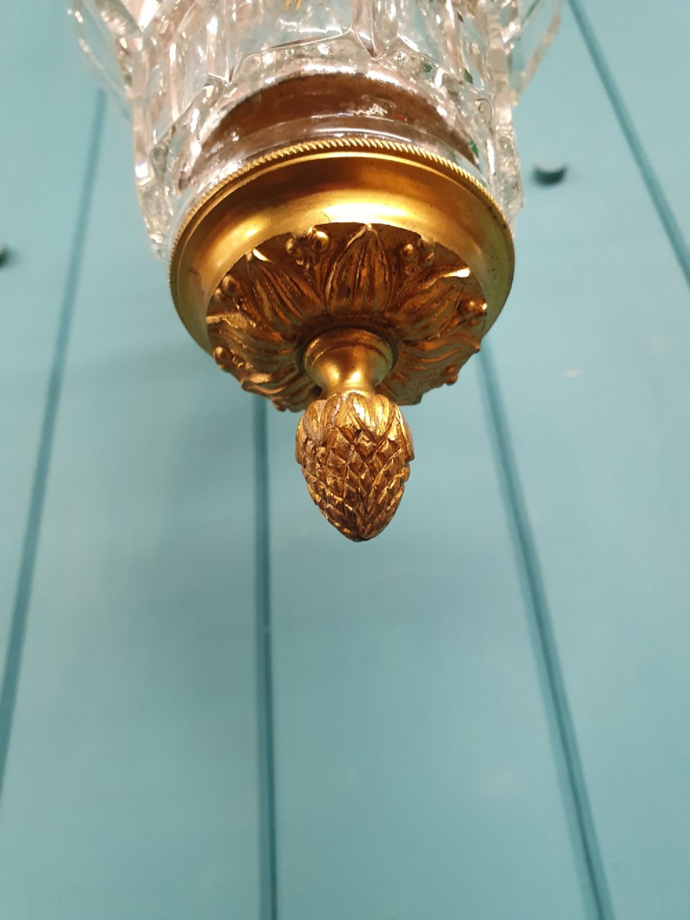 A French brass pendant lantern featuring a faceted moulded glass shade, ornate brass scroll crown, and suspension chain. View II