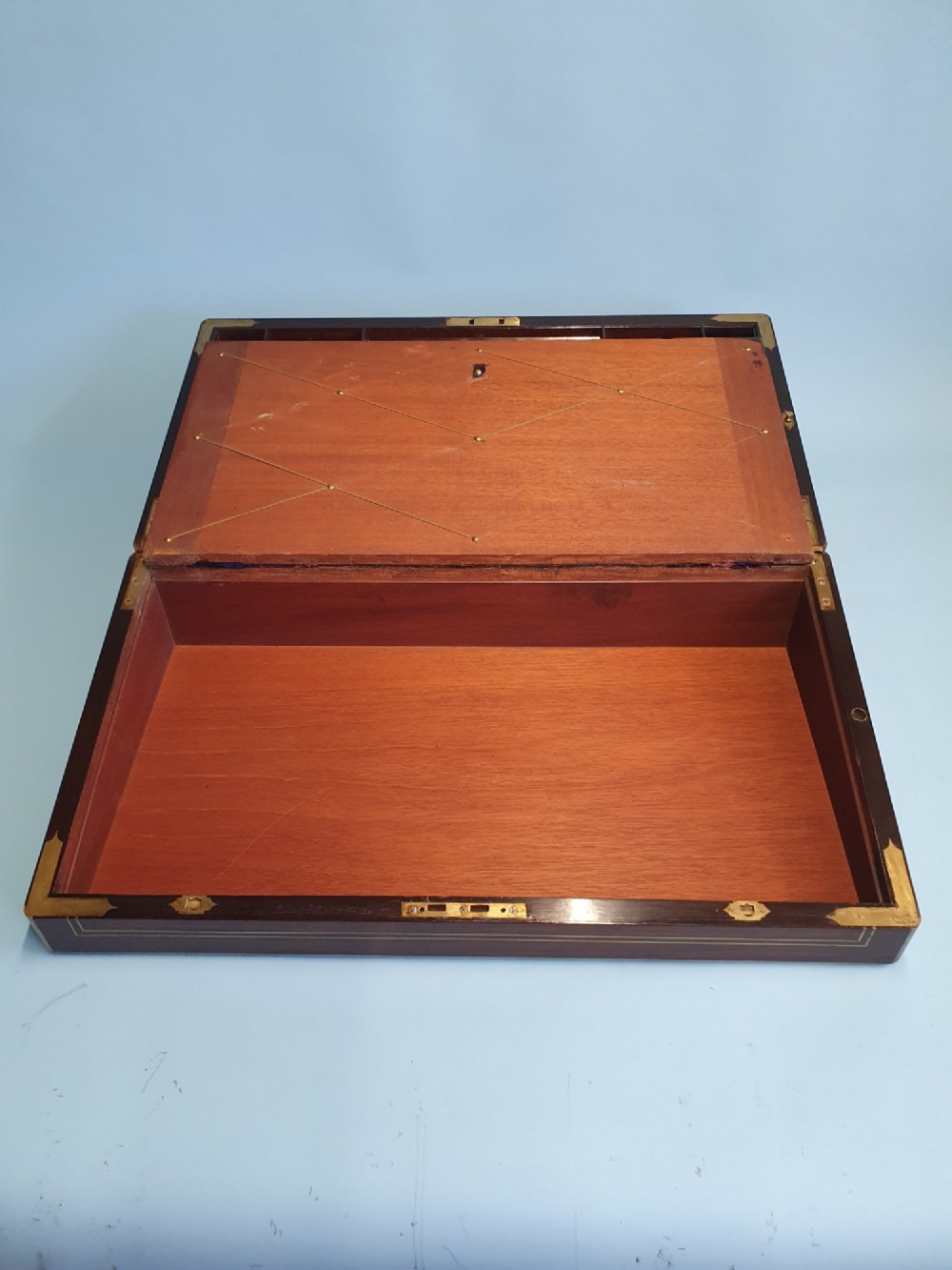 A rectangular dark rosewood writing slope featuring brass inlay stringing, brass corner brackets, a keyhole, and a central brass cartouche. View II