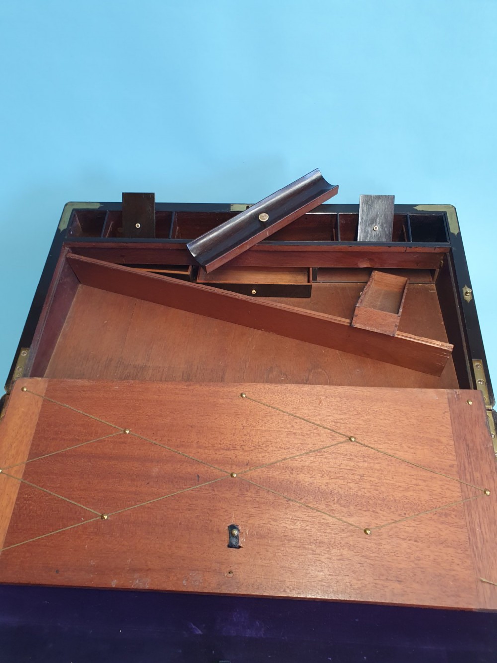 A rectangular dark rosewood writing slope featuring brass inlay stringing, brass corner brackets, a keyhole, and a central brass cartouche. View III