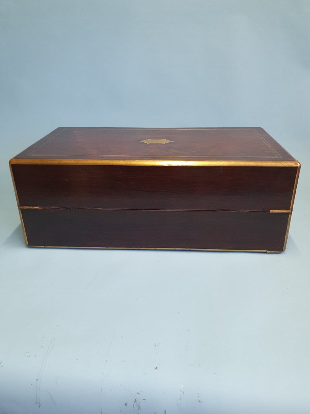 A rectangular dark rosewood writing slope featuring brass inlay stringing, brass corner brackets, a keyhole, and a central brass cartouche. View VIII