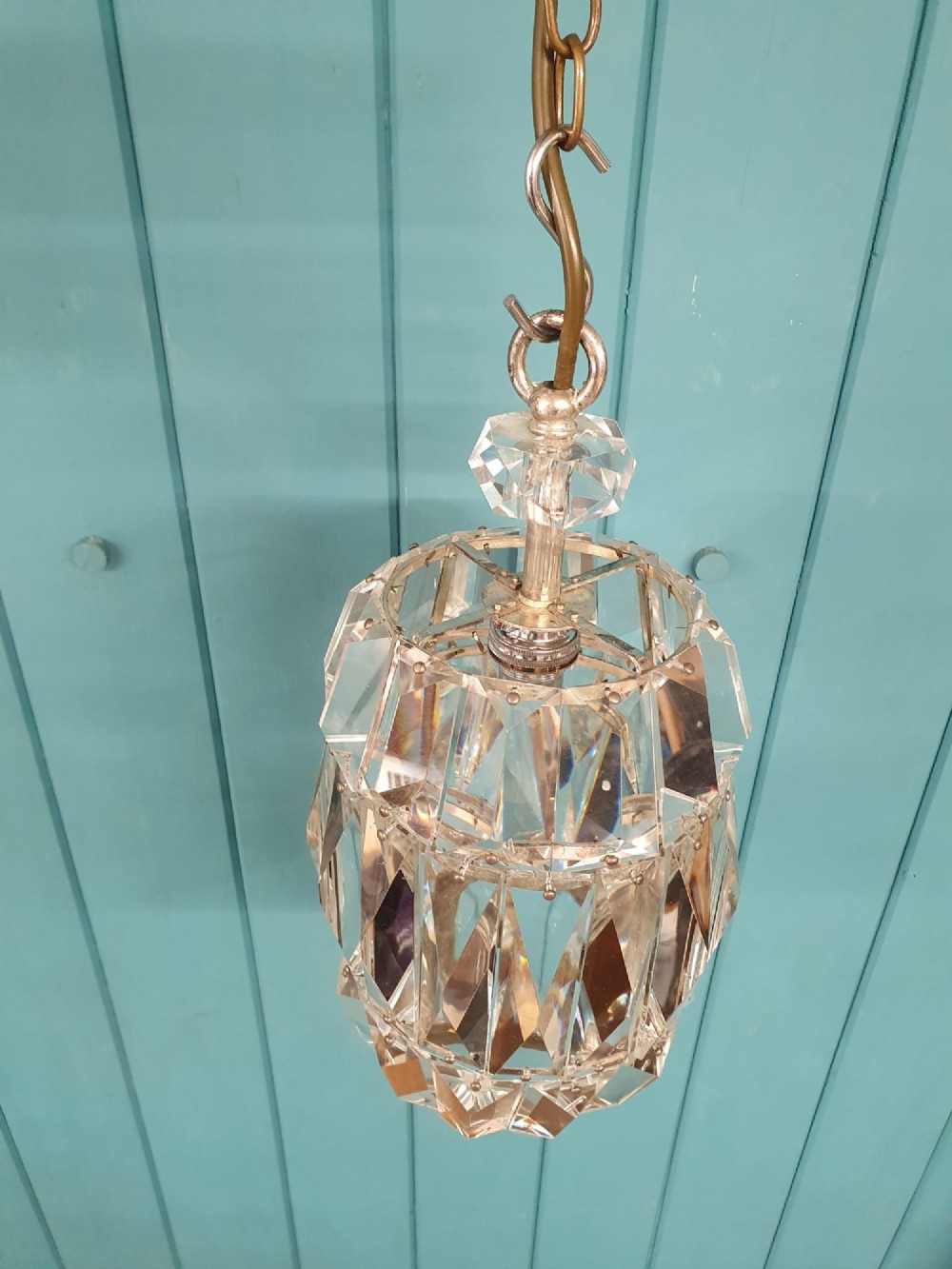 An early 20th-century small barrel-shaped crystal prism chandelier suspended by a brass link chain. View II