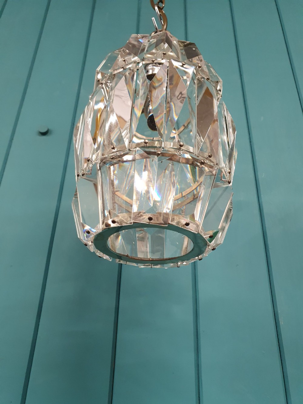 An early 20th-century small barrel-shaped crystal prism chandelier suspended by a brass link chain. View VI