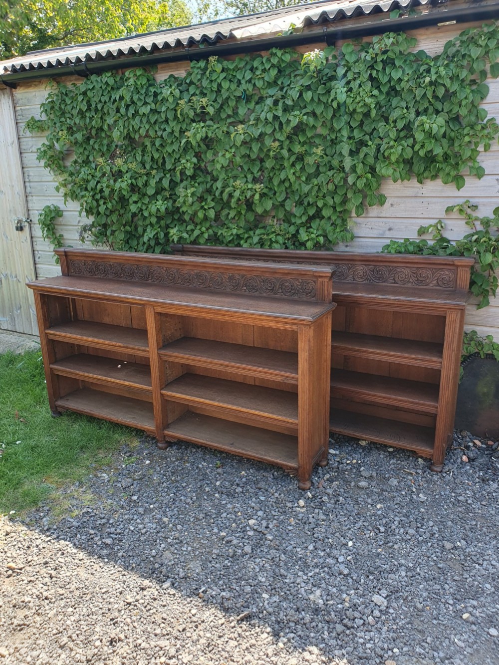 A pair of 19th-century low oak bookcases featuring carved scrollwork back galleries and open twin-bay shelving.