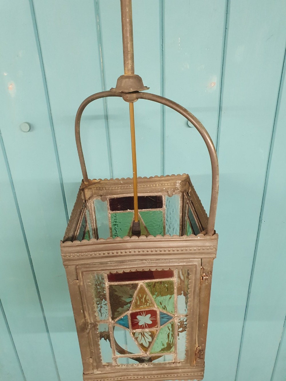 A Victorian hall lantern featuring a rectangular metal frame, an arched suspension handle, and leaded stained glass panels in green, red, and blue geometric patterns. View II