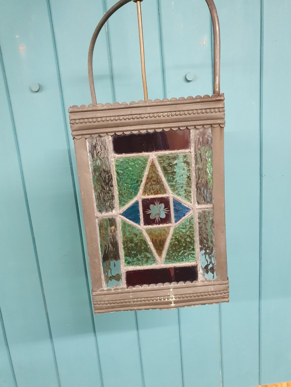 A Victorian hall lantern featuring a rectangular metal frame, an arched suspension handle, and leaded stained glass panels in green, red, and blue geometric patterns. View IV