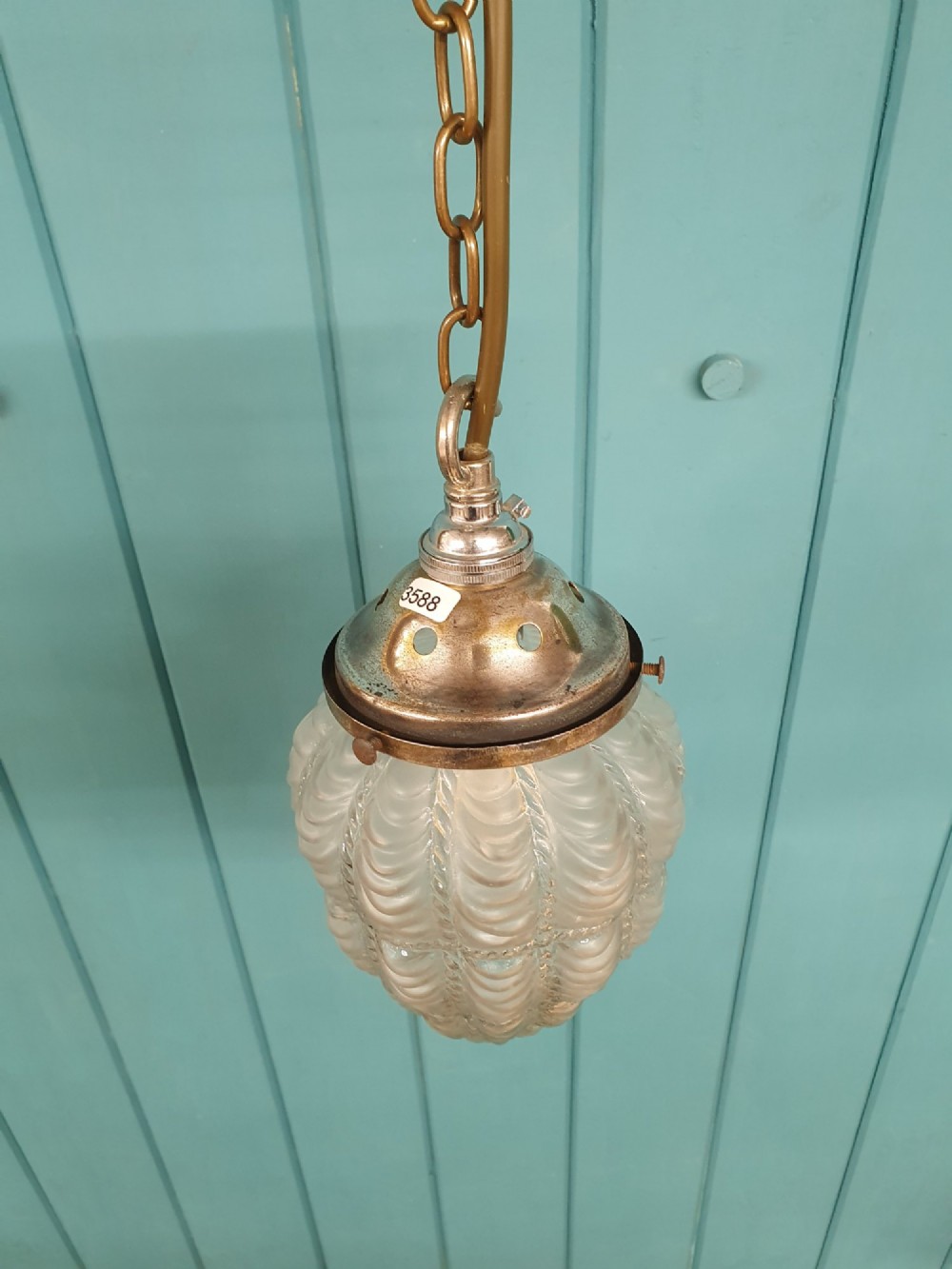 An antique moulded glass pendant light shade with a swag design hanging from a brass gallery and link chain. View III