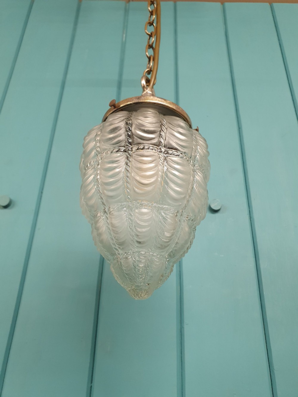 An antique moulded glass pendant light shade with a swag design hanging from a brass gallery and link chain. View V