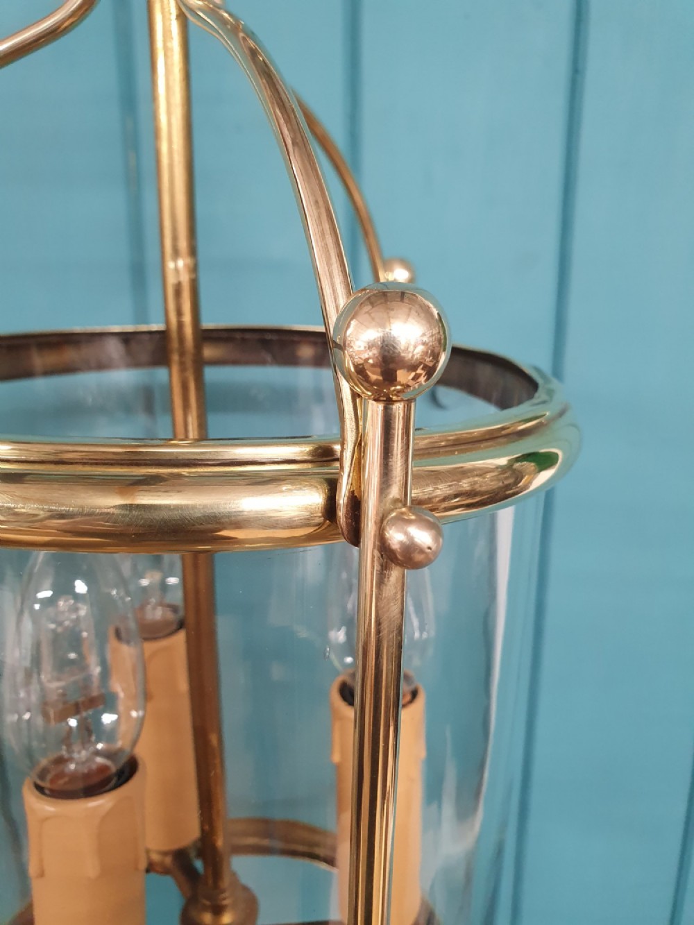 A brass cylindrical hanging hall lantern with clear glass panels, three central candle sleeves, and a suspended brass chain. View VI