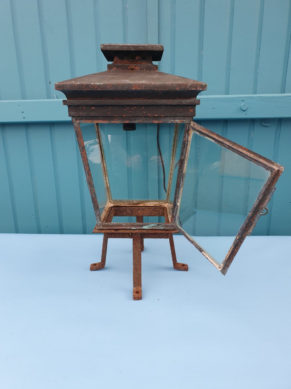 A Victorian weather-worn copper gas lantern converted for electric use, featuring clear glass panels and a stepped pyramidal top cowl supported by an iron mounting base. View II