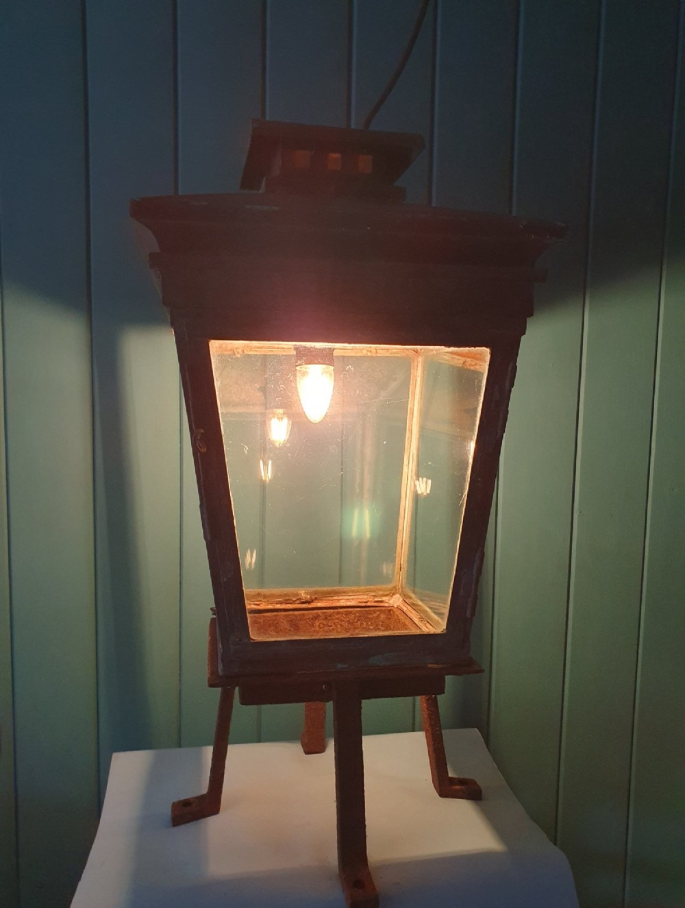 A Victorian weather-worn copper gas lantern converted for electric use, featuring clear glass panels and a stepped pyramidal top cowl supported by an iron mounting base. View VII