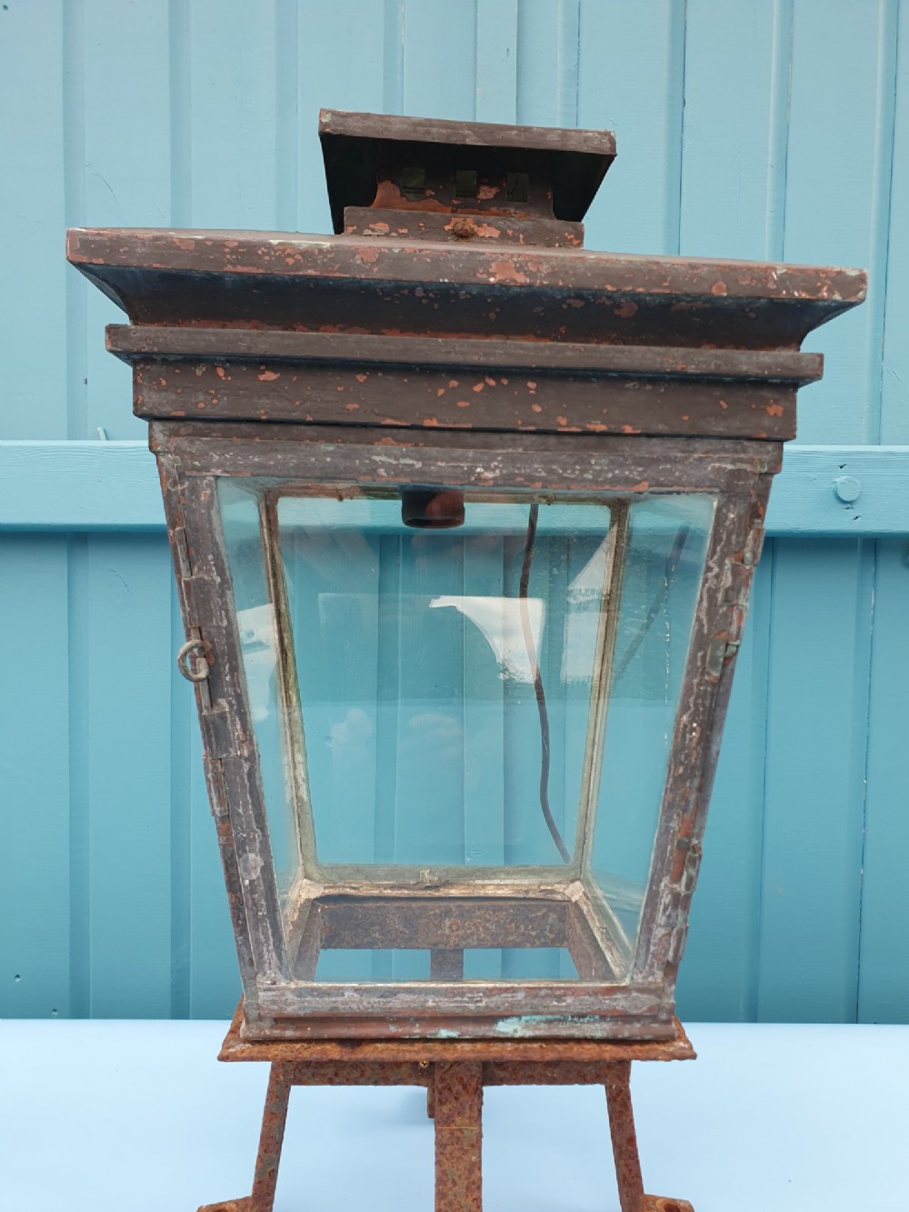 A Victorian weather-worn copper gas lantern converted for electric use, featuring clear glass panels and a stepped pyramidal top cowl supported by an iron mounting base. View VIII