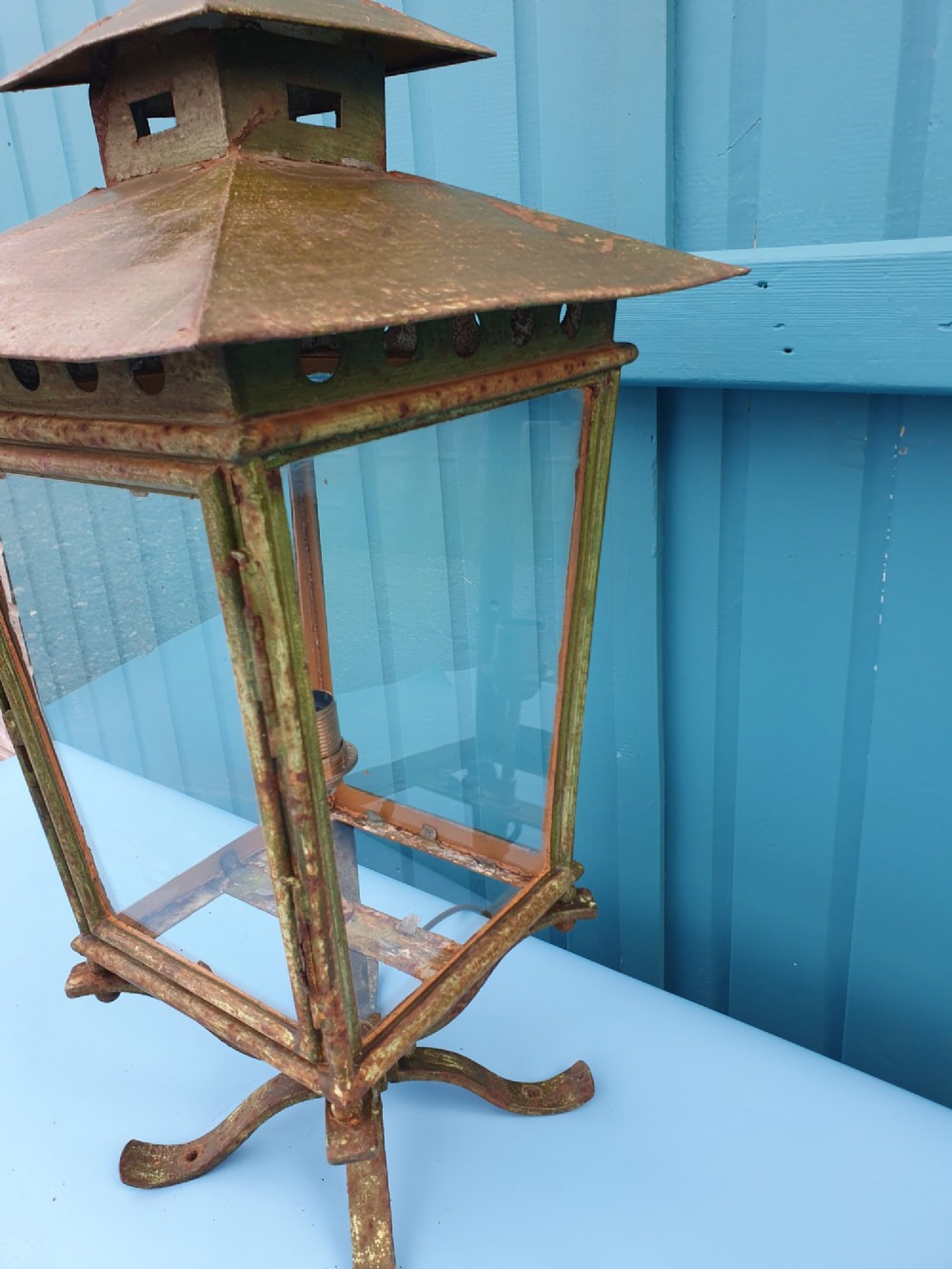 A Victorian green-painted metal garden lantern with glass panes and a tiered top cap, converted for electrical use and mounted on a decorative base. View II