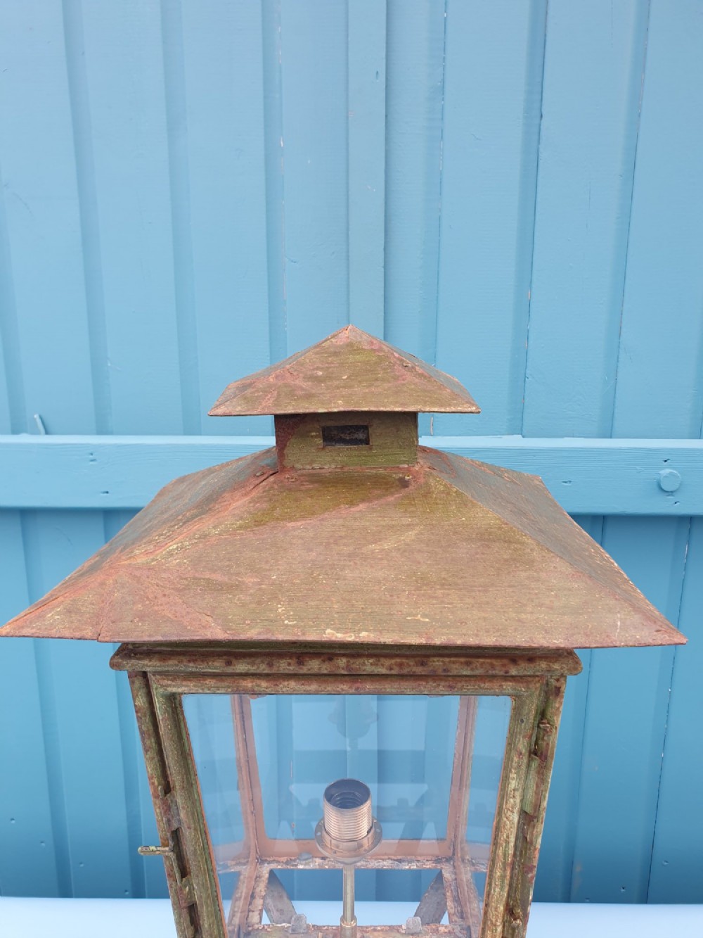 A Victorian green-painted metal garden lantern with glass panes and a tiered top cap, converted for electrical use and mounted on a decorative base. View III