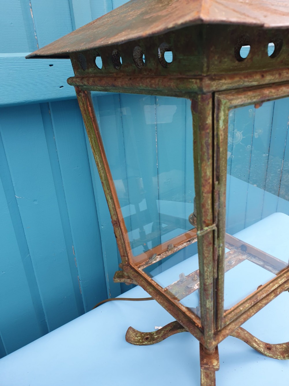 A Victorian green-painted metal garden lantern with glass panes and a tiered top cap, converted for electrical use and mounted on a decorative base. View VIII