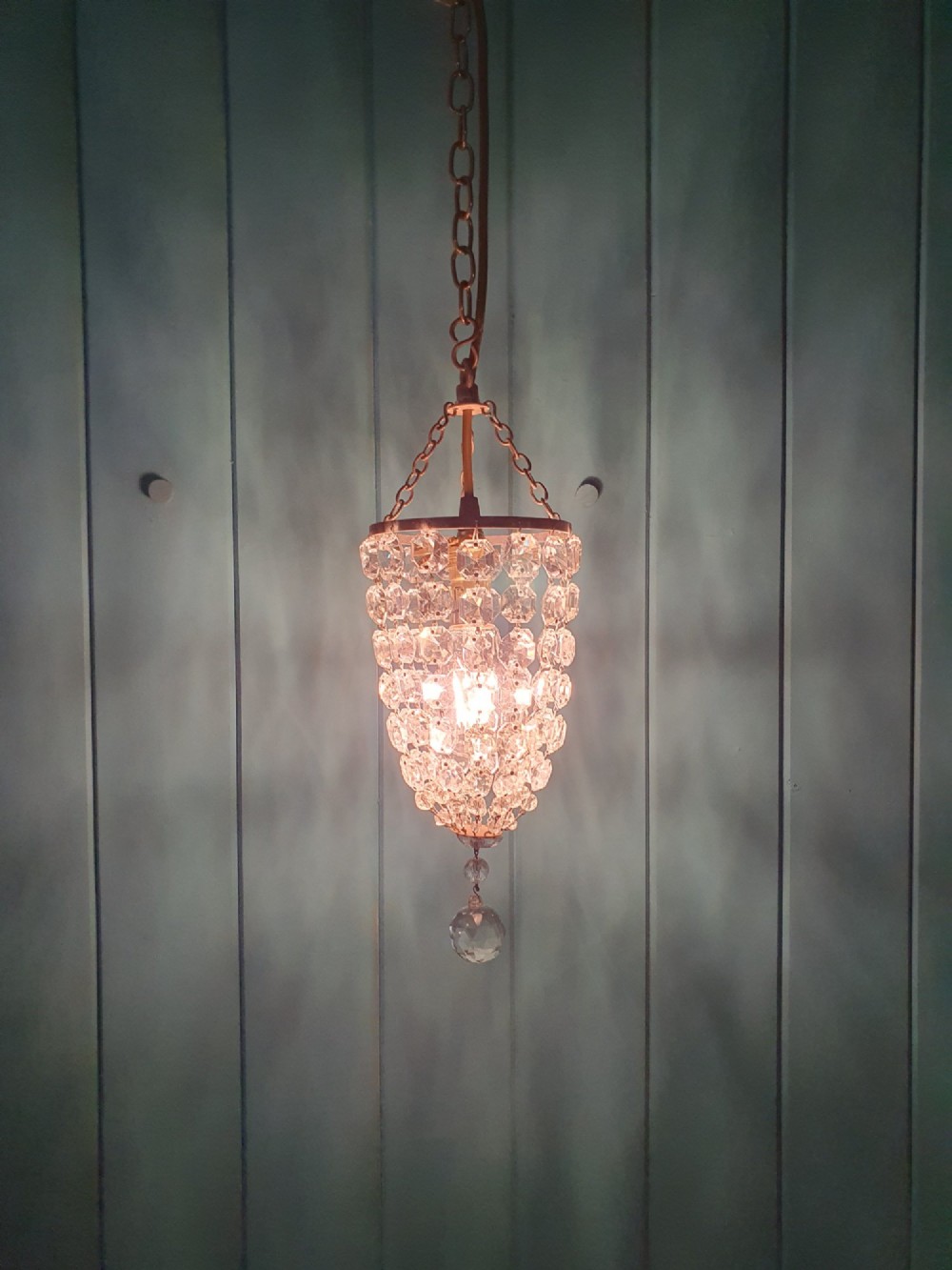 A small antique crystal bag chandelier featuring cascading faceted glass beads suspended from a circular brass frame with a chain. View II
