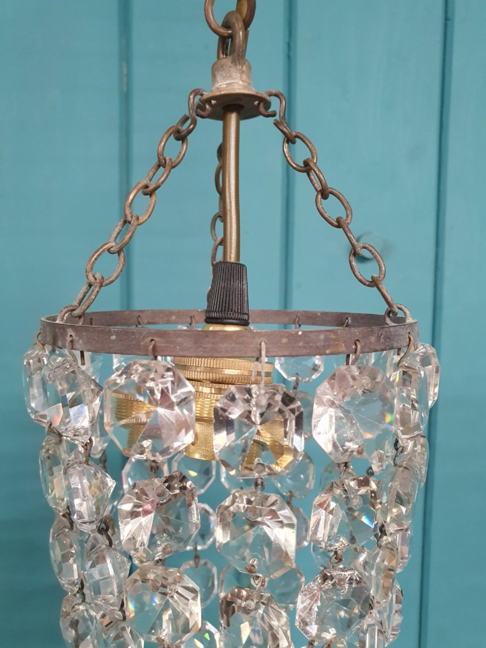 A small antique crystal bag chandelier featuring cascading faceted glass beads suspended from a circular brass frame with a chain. View III
