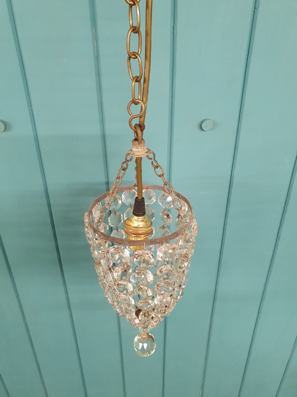 A small antique crystal bag chandelier featuring cascading faceted glass beads suspended from a circular brass frame with a chain. View IV