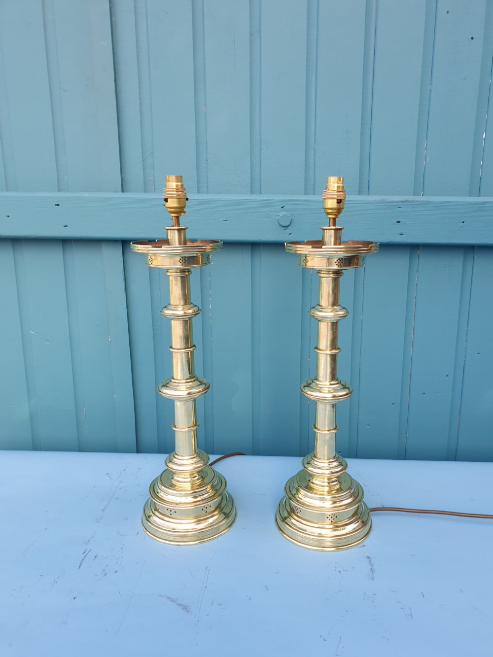 A pair of turned brass column table lamps topped with cylindrical bright pink fabric shades. View VII