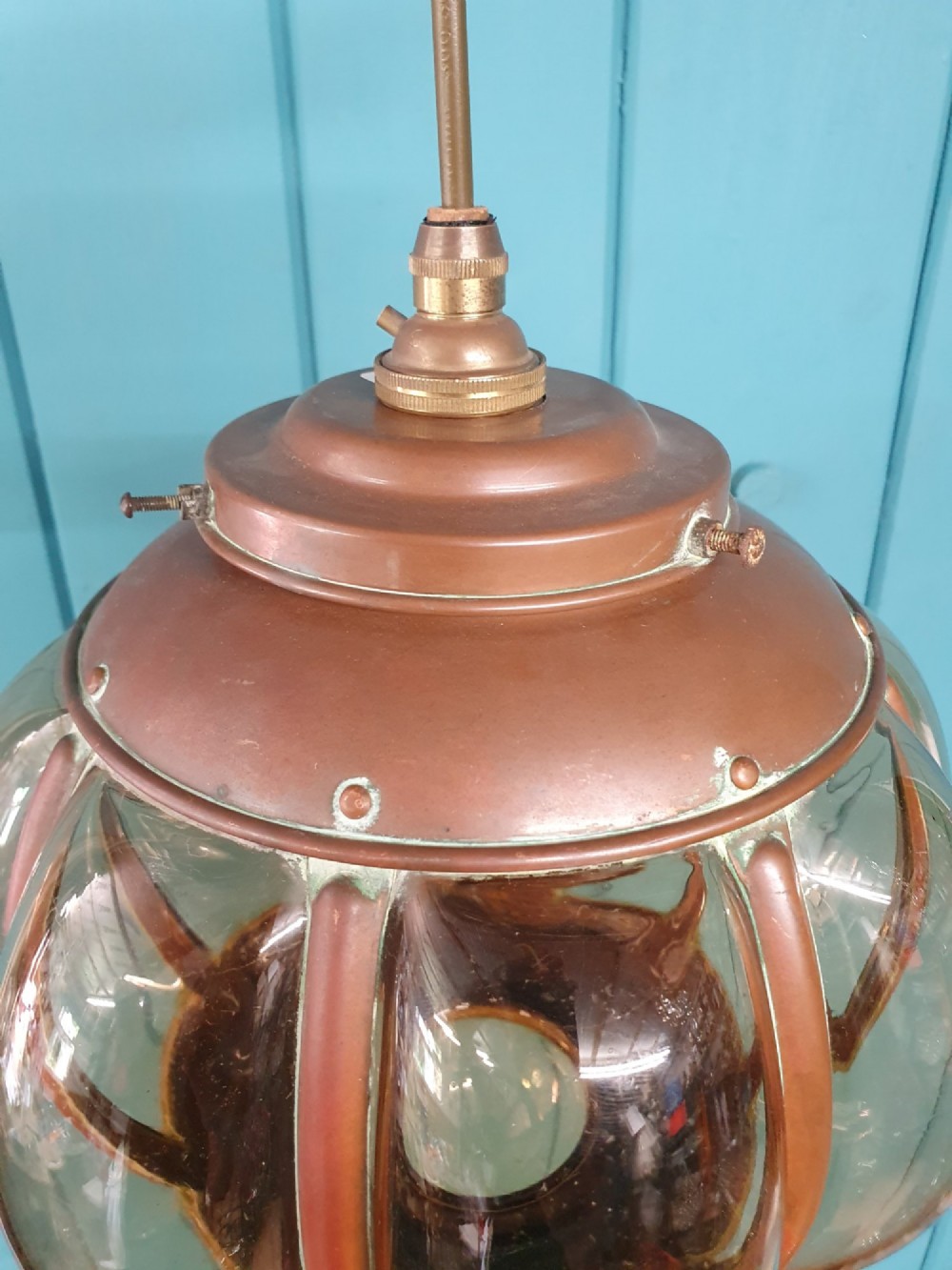 A spherical nautical pendant light featuring a copper cap and framed body enclosing a ribbed smoked amber glass globe. View III