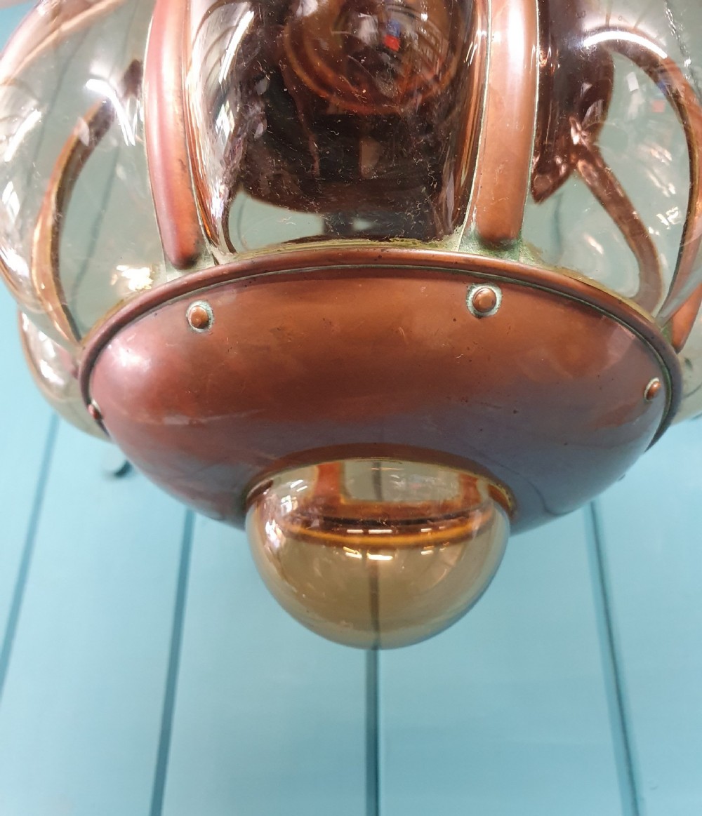 A spherical nautical pendant light featuring a copper cap and framed body enclosing a ribbed smoked amber glass globe. View IV