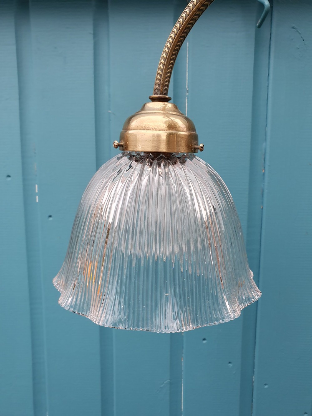 An antique brass three-arm rise and fall chandelier with fluted clear glass shades and scrolled metalwork detailing. View II