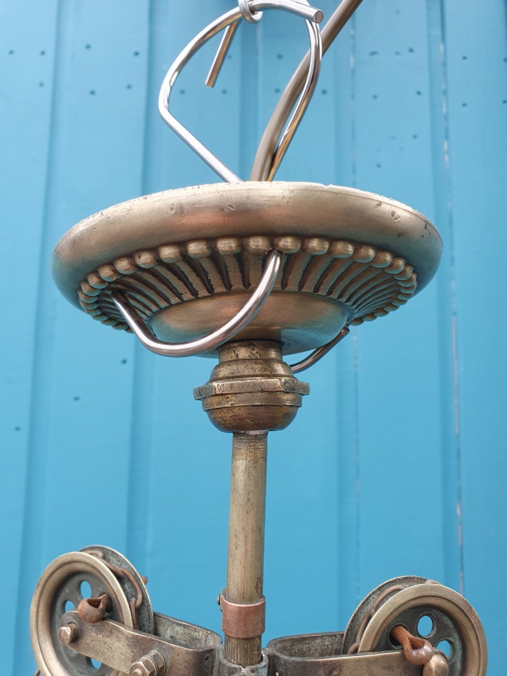 An antique brass three-arm rise and fall chandelier with fluted clear glass shades and scrolled metalwork detailing. View IV