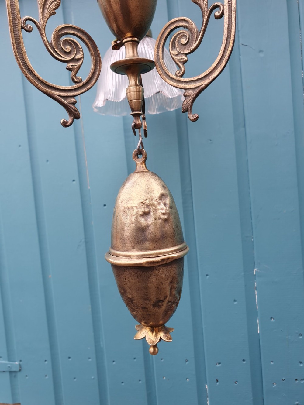 An antique brass three-arm rise and fall chandelier with fluted clear glass shades and scrolled metalwork detailing. View VI