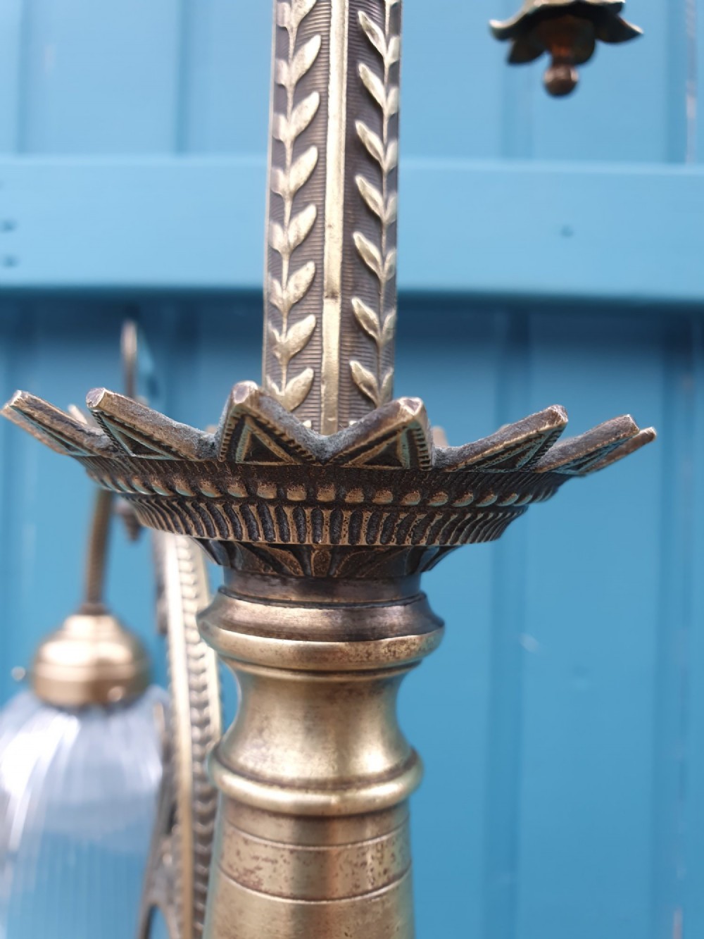 An antique brass three-arm rise and fall chandelier with fluted clear glass shades and scrolled metalwork detailing. View IX