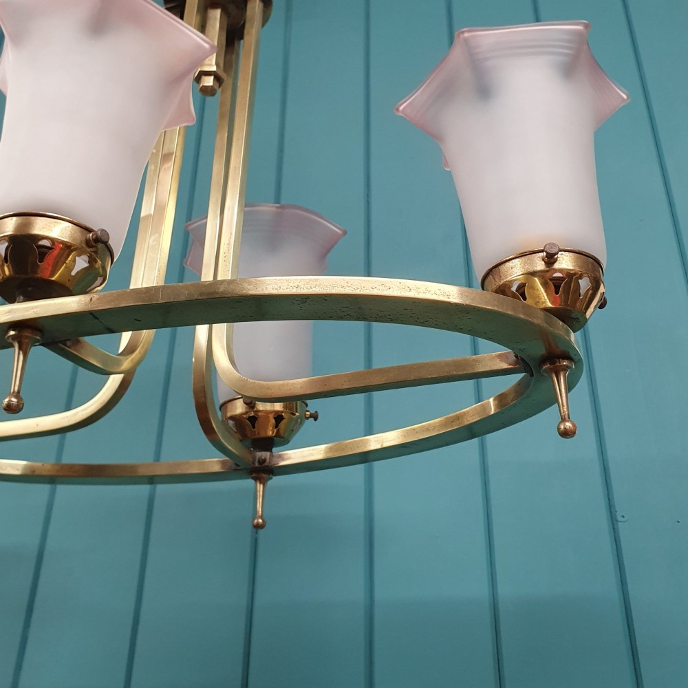An Art Deco brass four-light chandelier featuring a circular brass frame suspending four tulip-shaped pink frosted glass shades with ruffled rims. View II