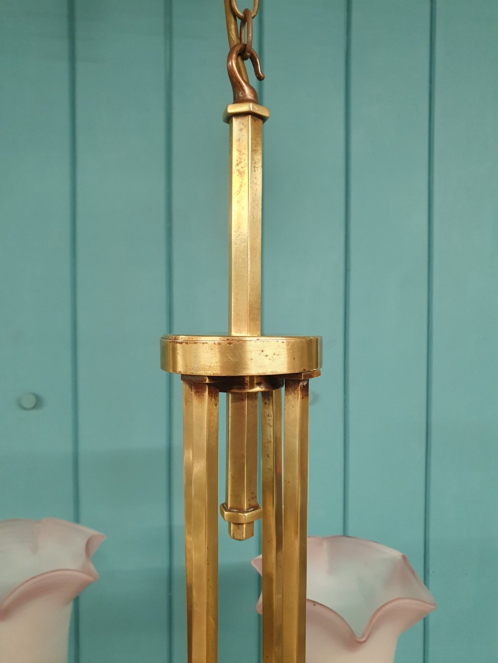 An Art Deco brass four-light chandelier featuring a circular brass frame suspending four tulip-shaped pink frosted glass shades with ruffled rims. View III