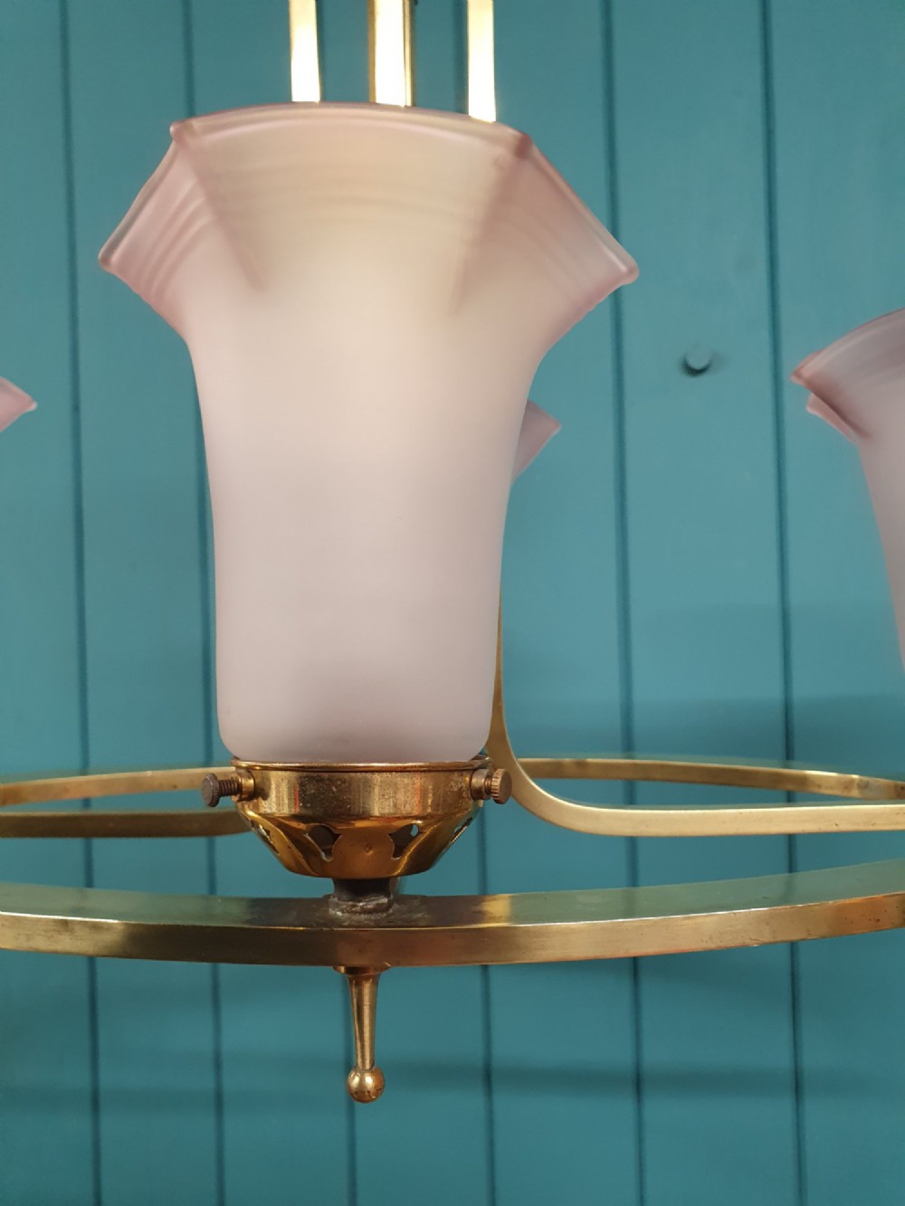 An Art Deco brass four-light chandelier featuring a circular brass frame suspending four tulip-shaped pink frosted glass shades with ruffled rims. View VI