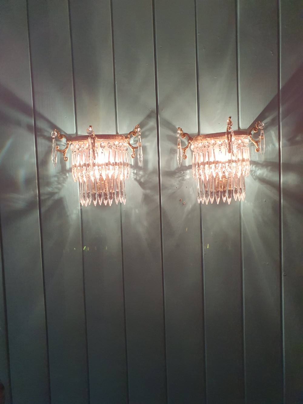 A pair of antique gilt brass wall lights featuring cascading concentric tiers of pointed crystal glass prisms. View V